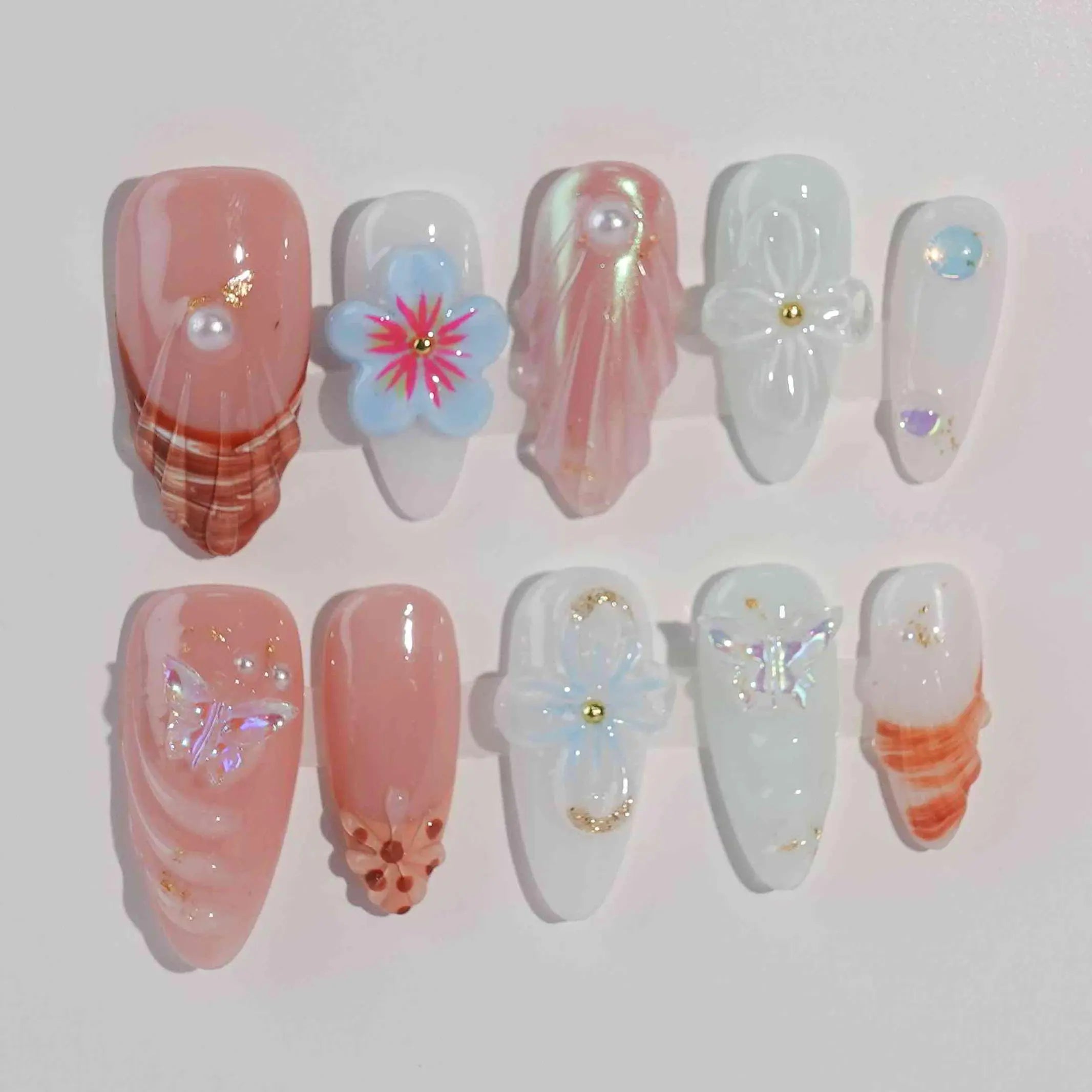 Medium almond press-on nails with coral wave designs, pink 3D flowers, and crystal accents for summer.