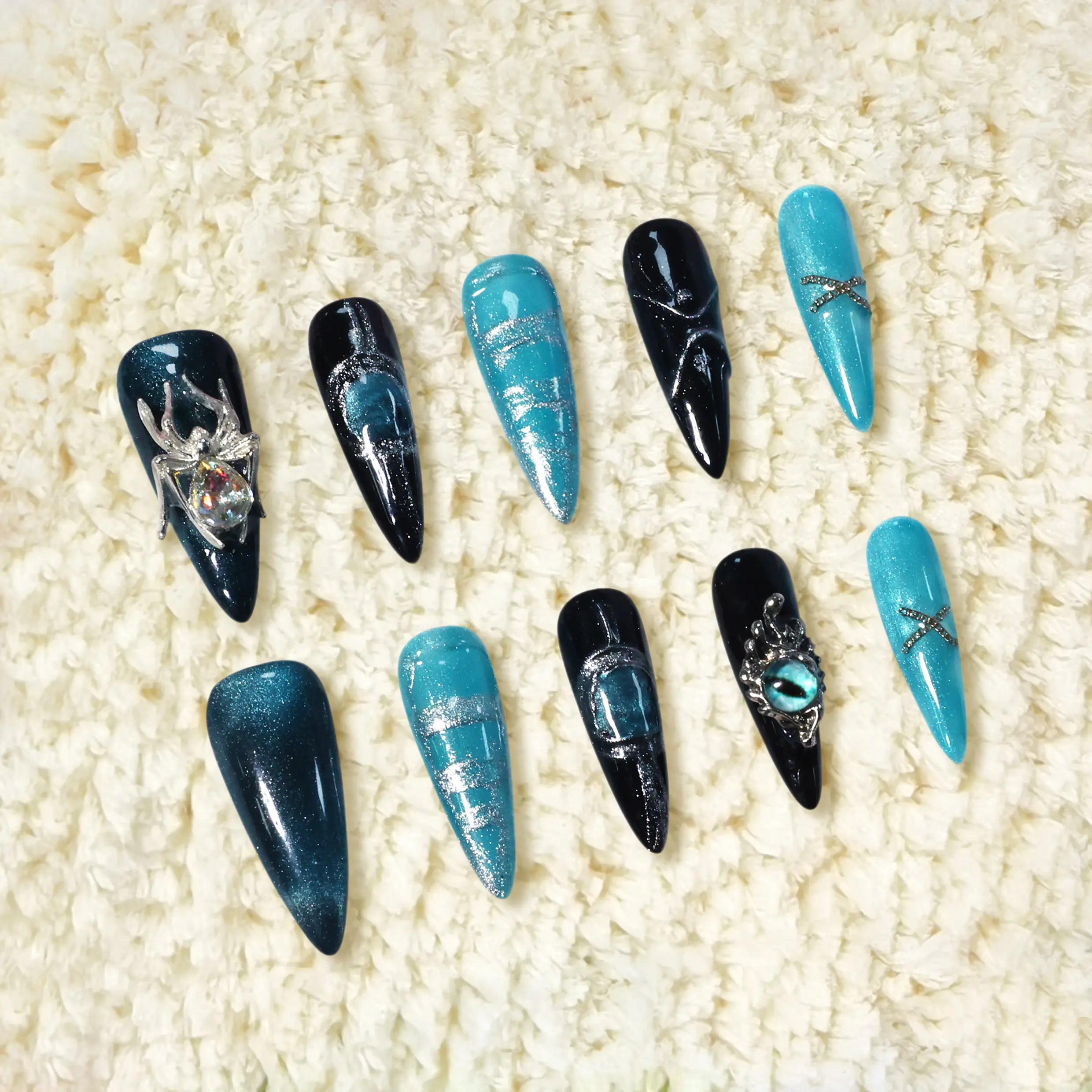 Black and silver stiletto press on nails with icy turquoise tones, 3D spider and snake charms, and marbled metallic accents.