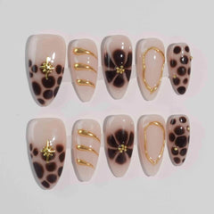Almond-shaped black press on nails with animal print and golden wire accents.