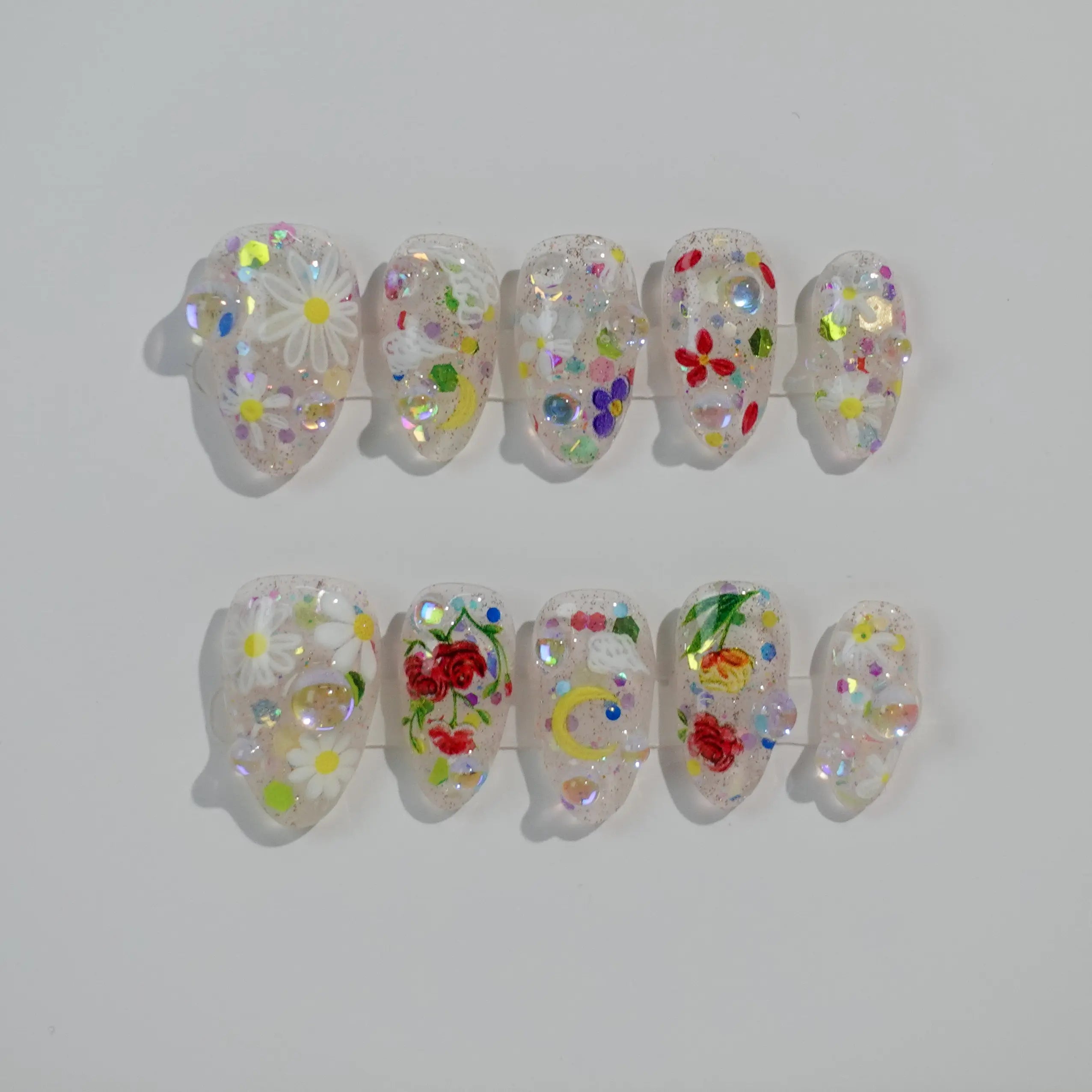 Clear almond press on nails with holographic flowers and shimmer, perfect for summer parties.