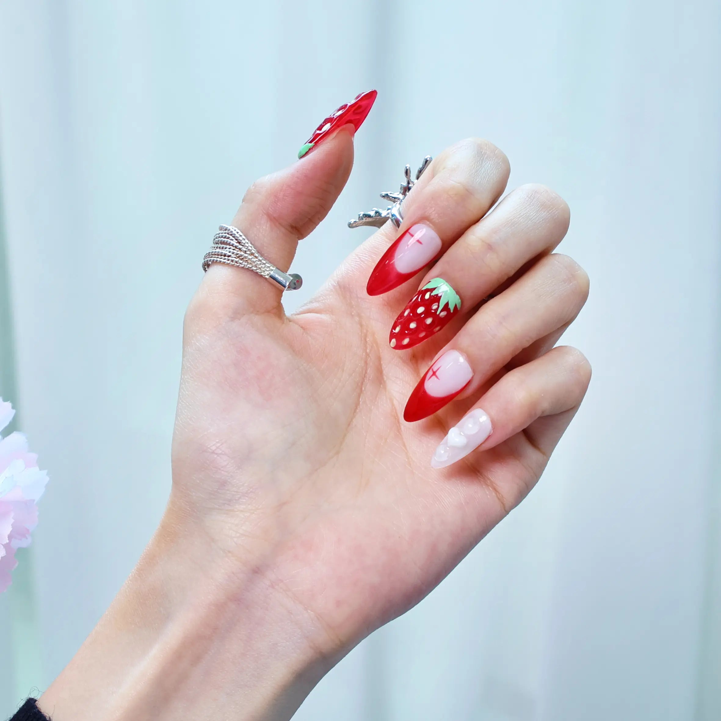 Close-up of glossy ombré nails with raised strawberry charms and shimmering heart-shaped pearl details
