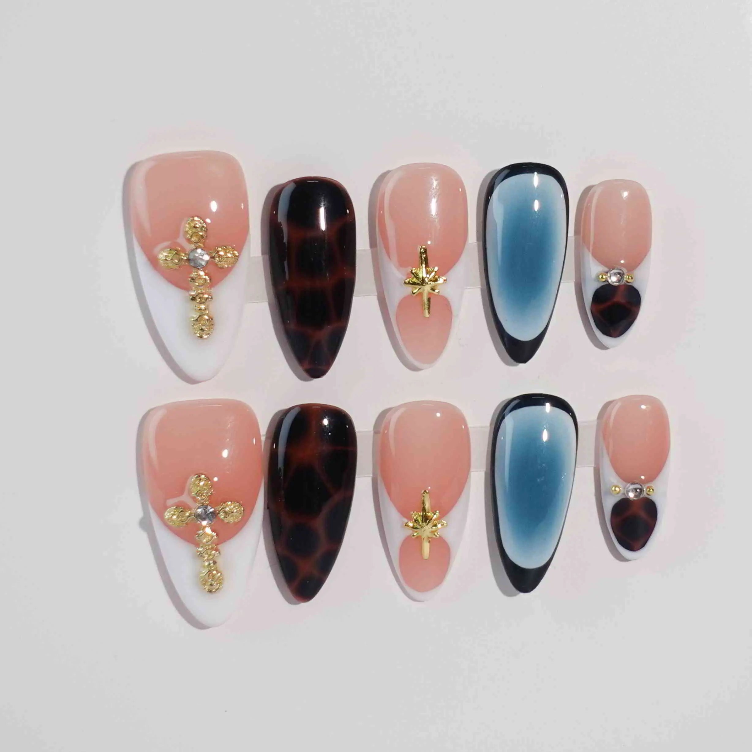 Almond-shaped black and nude press on nails with gold flower accents and tortoiseshell details.