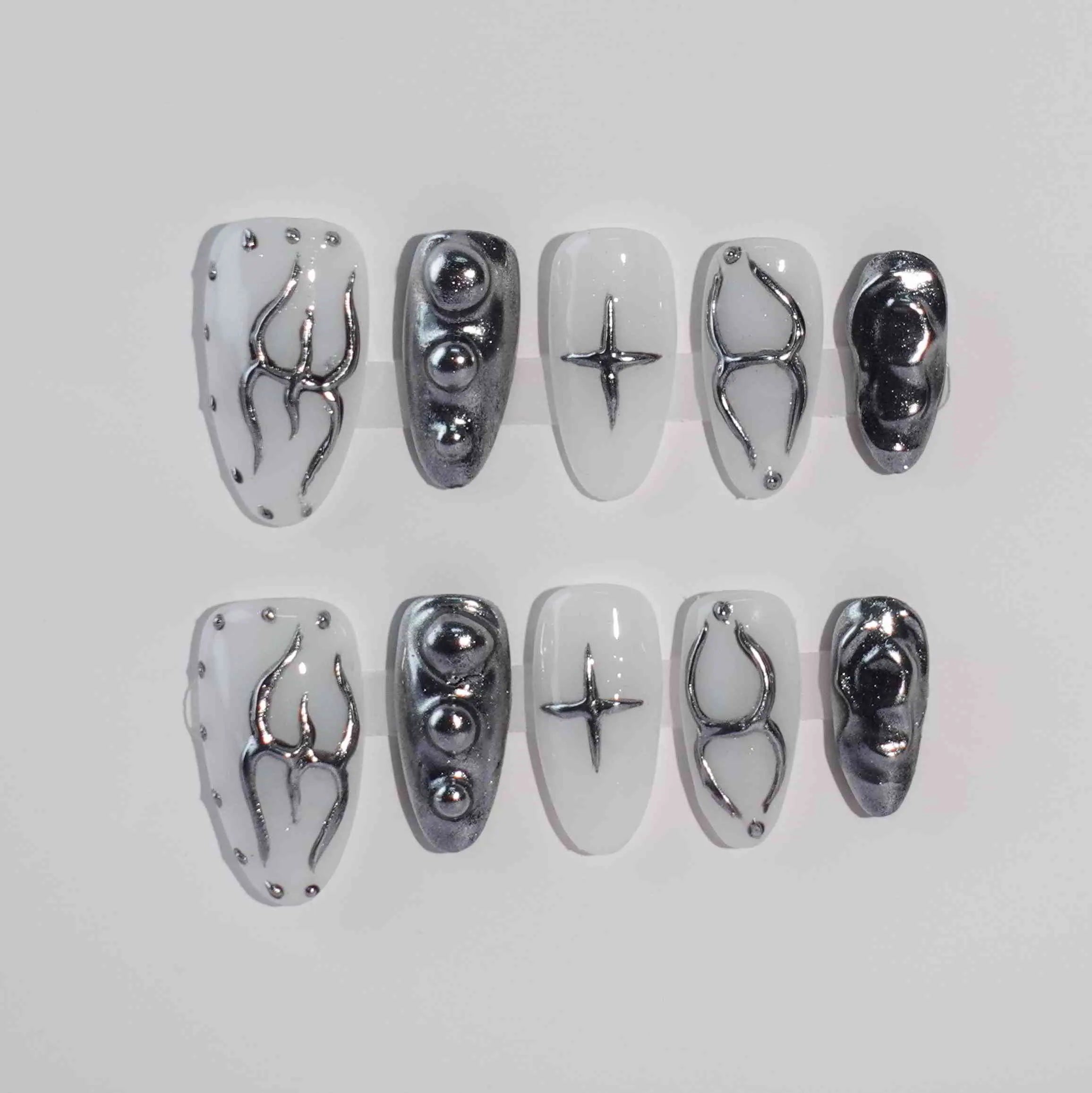 Almond-shaped black press on nails with white and chrome accents, featuring wire detail for a futuristic look.