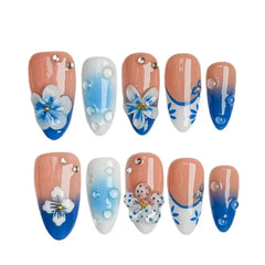Medium almond french tip press on nails with blue daisy flowers and pearl decorations.