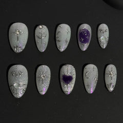 Medium almond press on nails with silver glitter, blue tones, and gemstone accents.