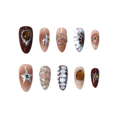 Medium almond press-on nails in warm mocha tones with amber gems, chrome stars, and milky way swirls for a cosmic-inspired look.