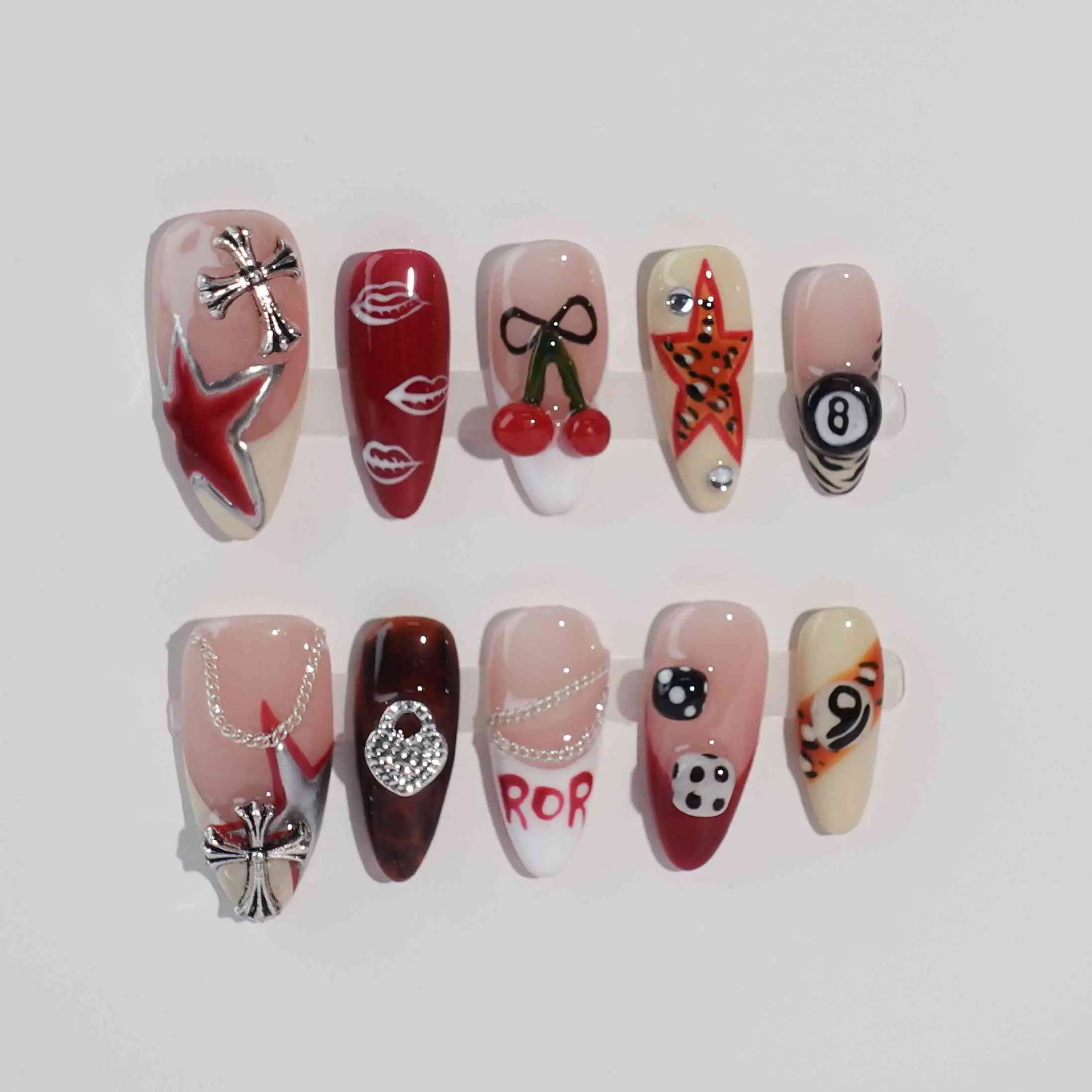 Glossy red medium almond press on nails with cherry, skull, dice, and star art in a punk-inspired style.
