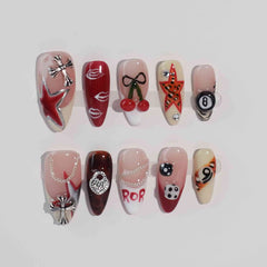 Glossy red medium almond press on nails with cherry, skull, dice, and star art in a punk-inspired style.