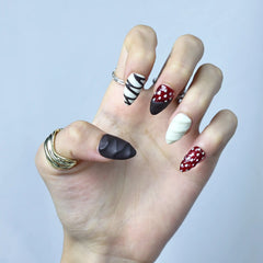 Almond-shaped nails with black-and-white marbled twists, matte finish, and strawberry-themed embellishments