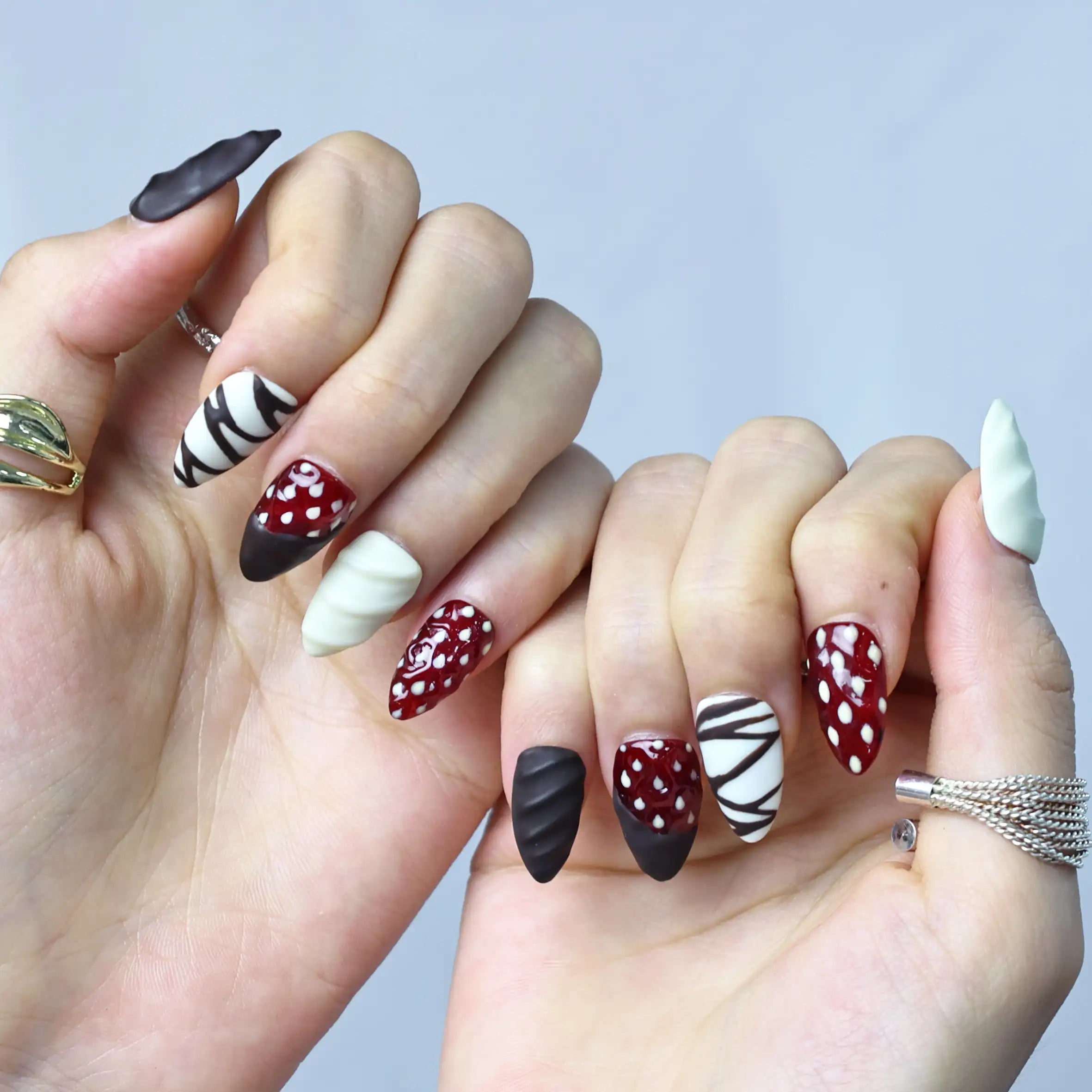 Side view of press-on manicure with rich swirl patterns and sculpted strawberries for a playful dessert look