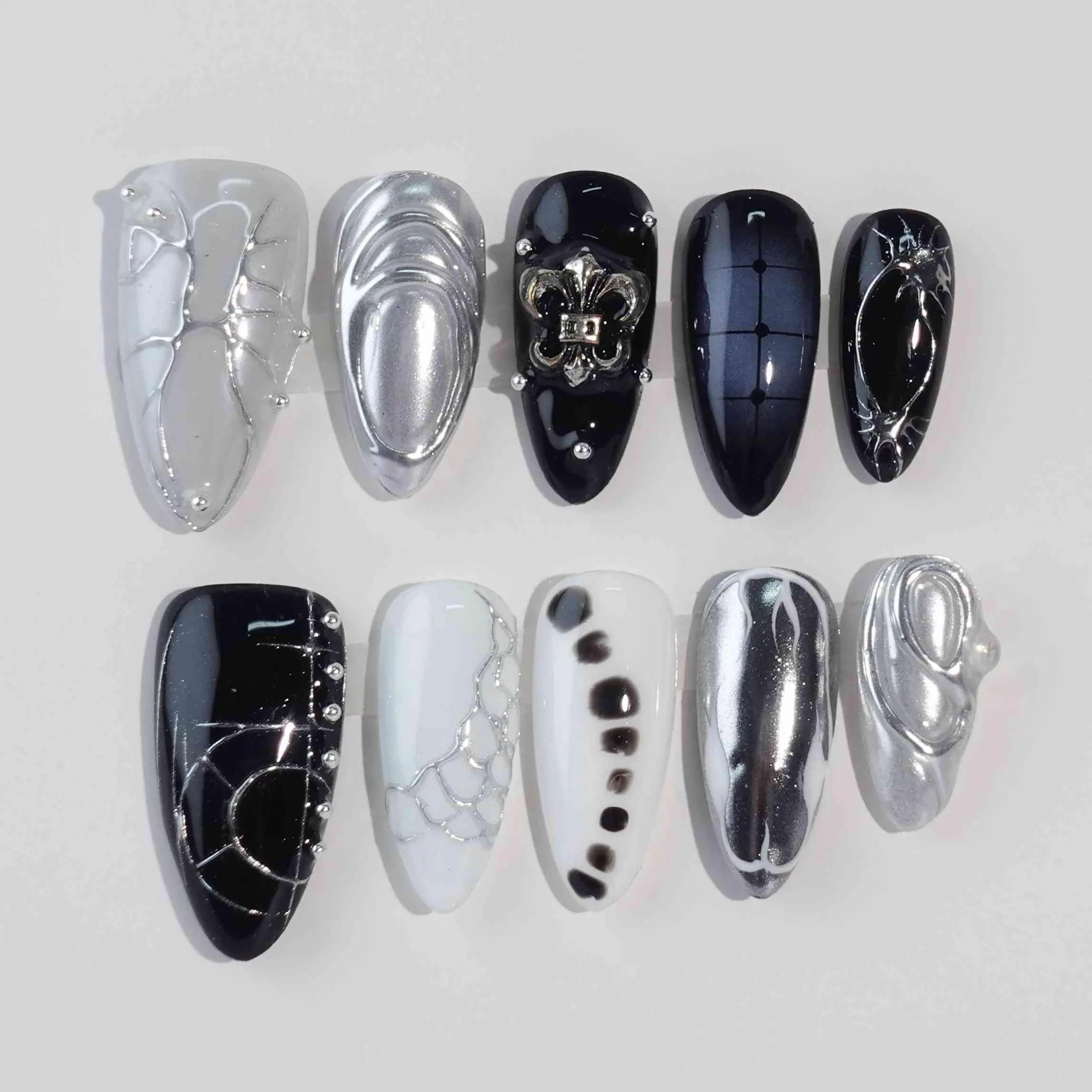 Metallic chrome black almond press-on nails with gemstone accents and high-gloss finish.