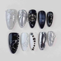 Metallic chrome black almond press-on nails with gemstone accents and high-gloss finish.