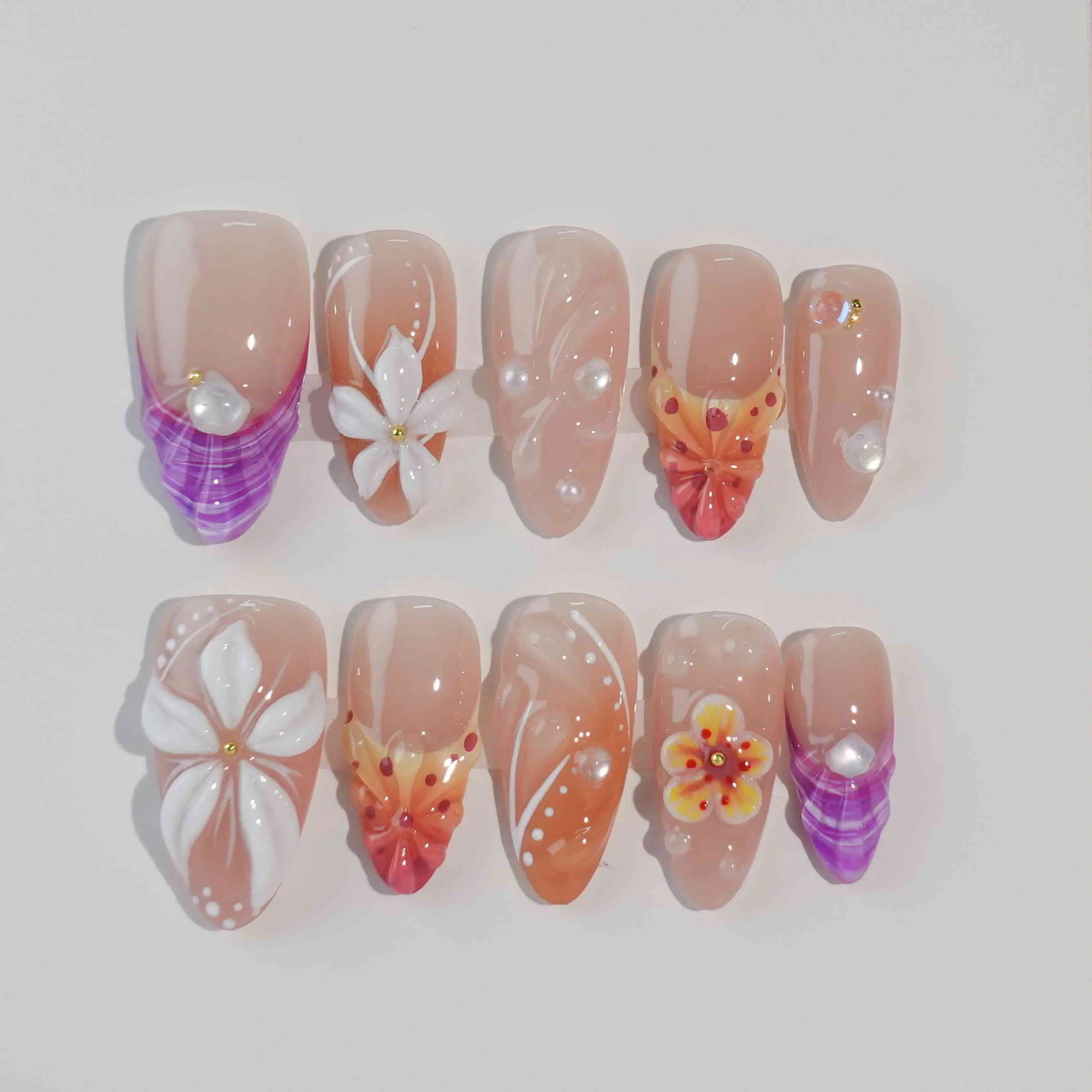 Almond-shaped summer press on nails with orange floral designs, clear French tips, and warm gradient colors.