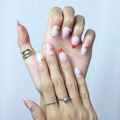 Close-up of almond-shaped pink nails with subtle glitter and 3D seashell charm details