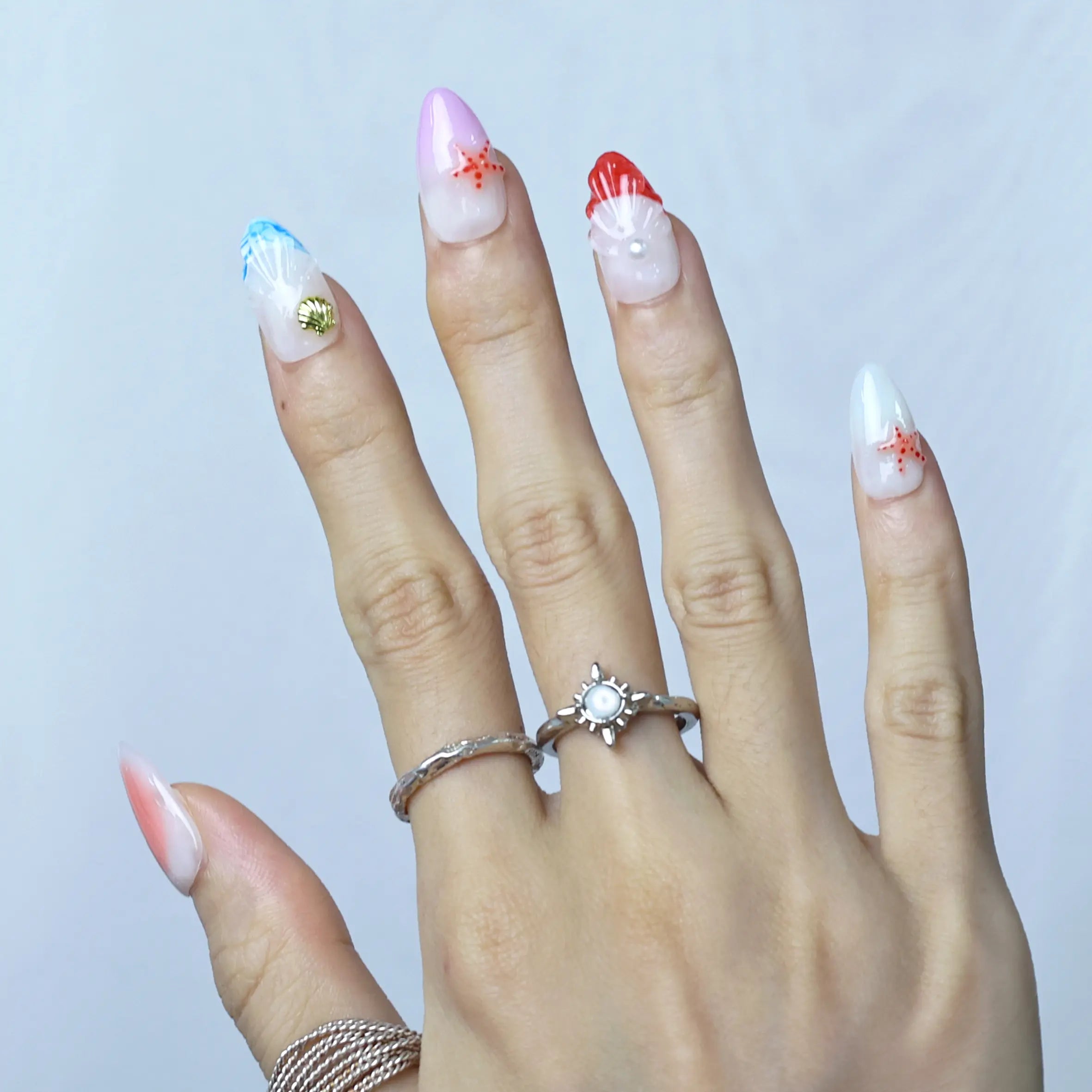 Side view of summer-themed almond nails with soft gradient and seashell decor