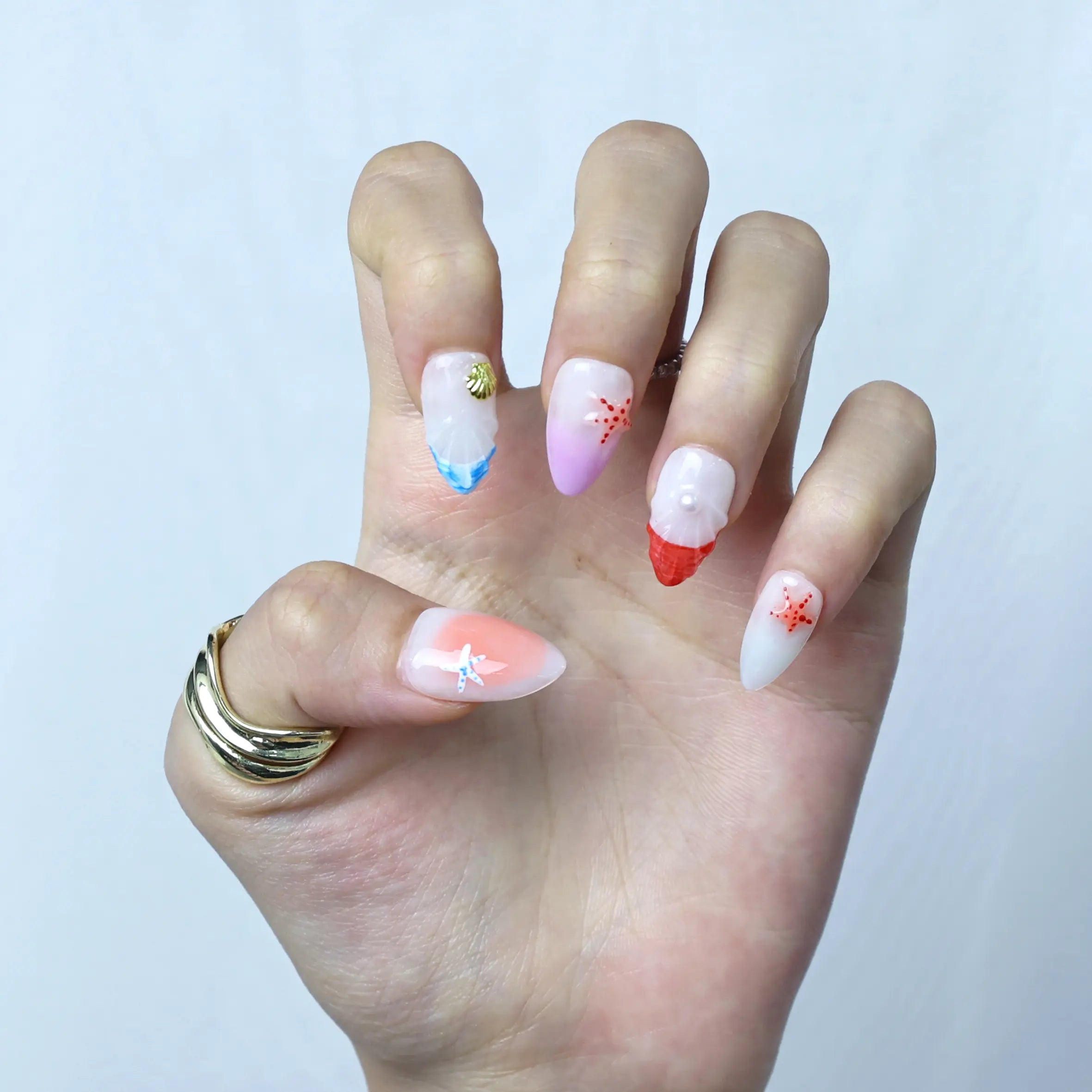 Pink and coral press-ons worn by model, featuring shimmering finish and oceanic accents