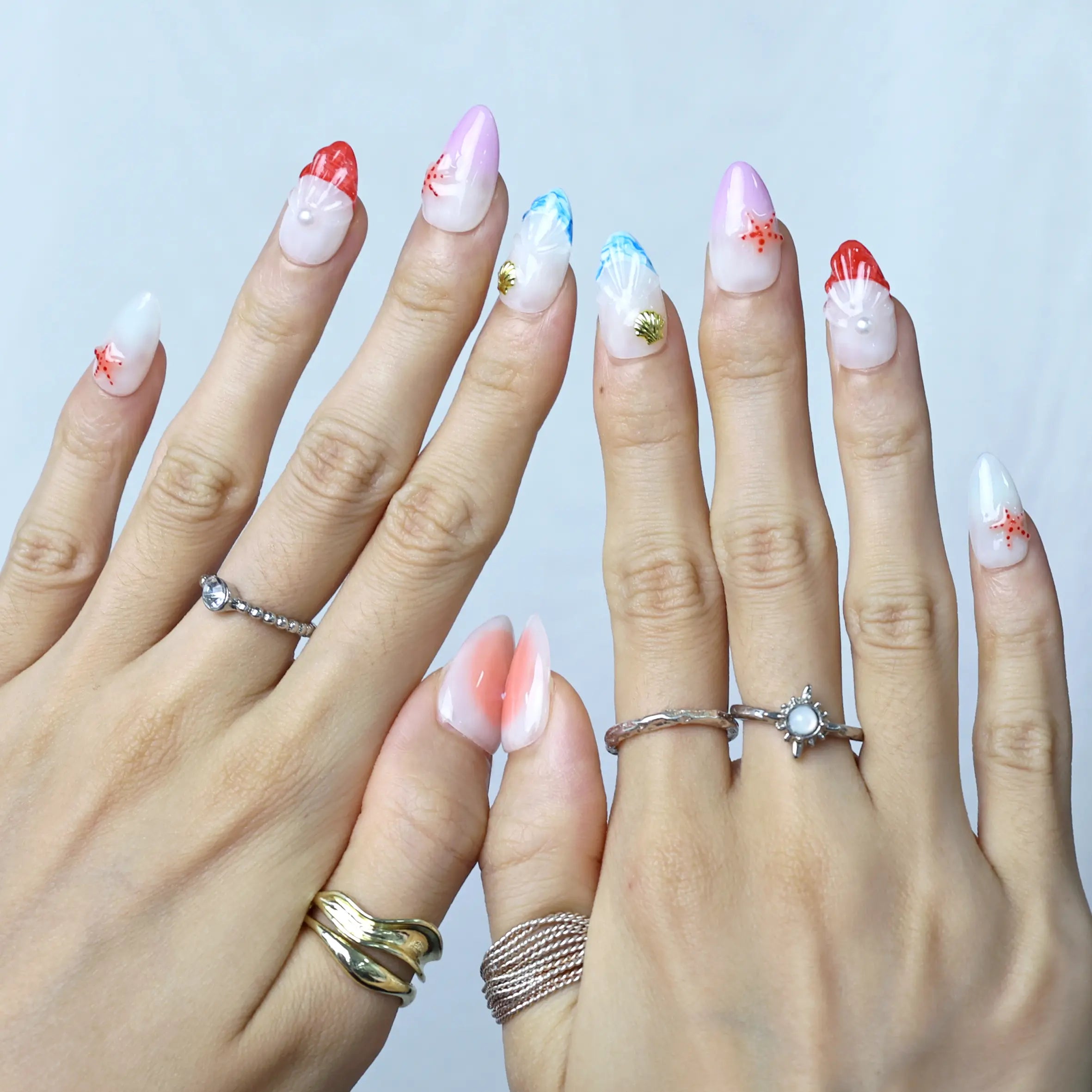 Glossy almond nails with a beachy gradient and delicate seashell touches, perfect for summer