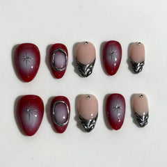 Medium almond-shaped red press on nails with french tips and rhinestone accents.