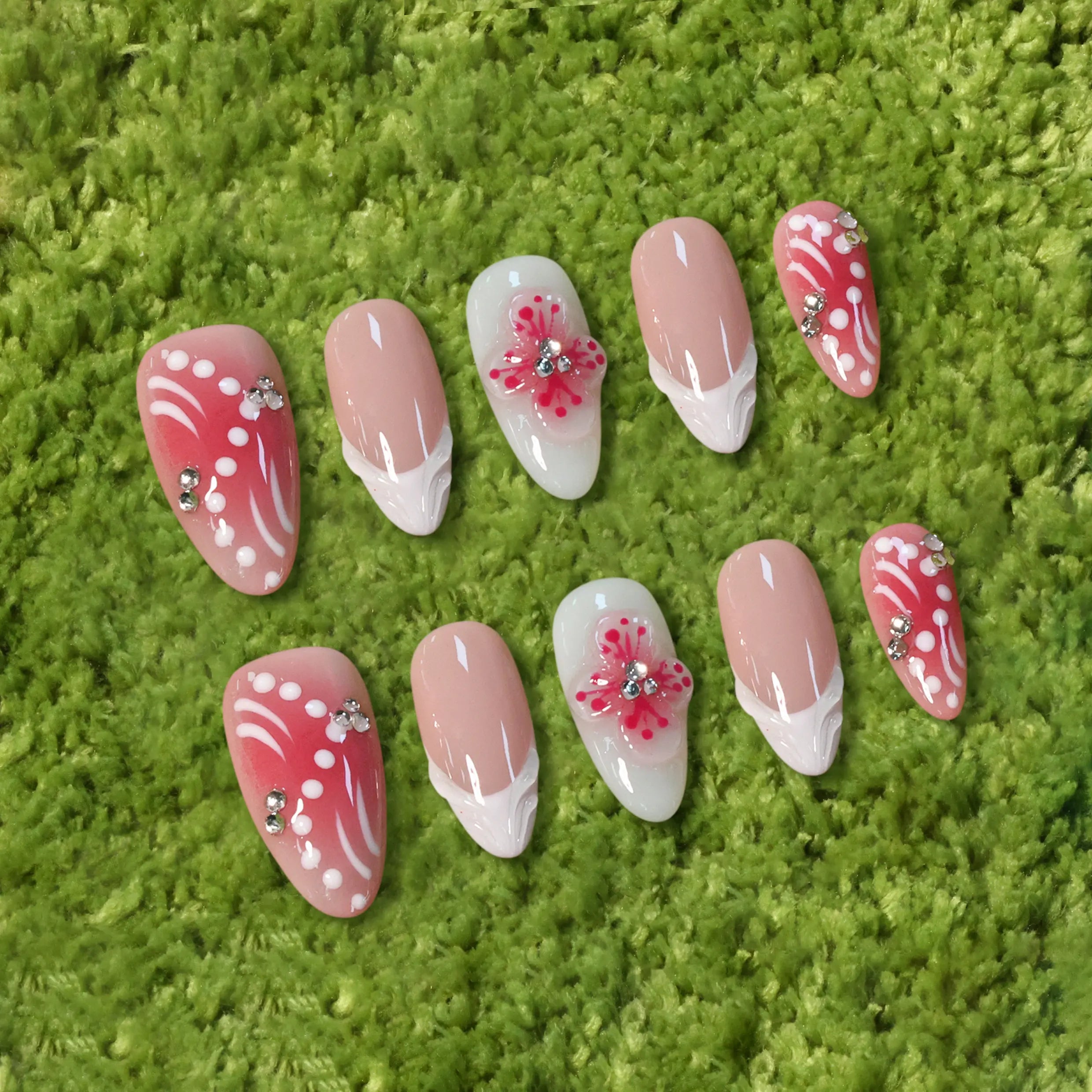 Medium pink almond press-on nails with French tips, 3D flowers, and rhinestones.