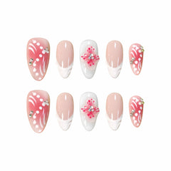 Medium pink almond press-on nails with French tips, 3D flowers, and rhinestones.