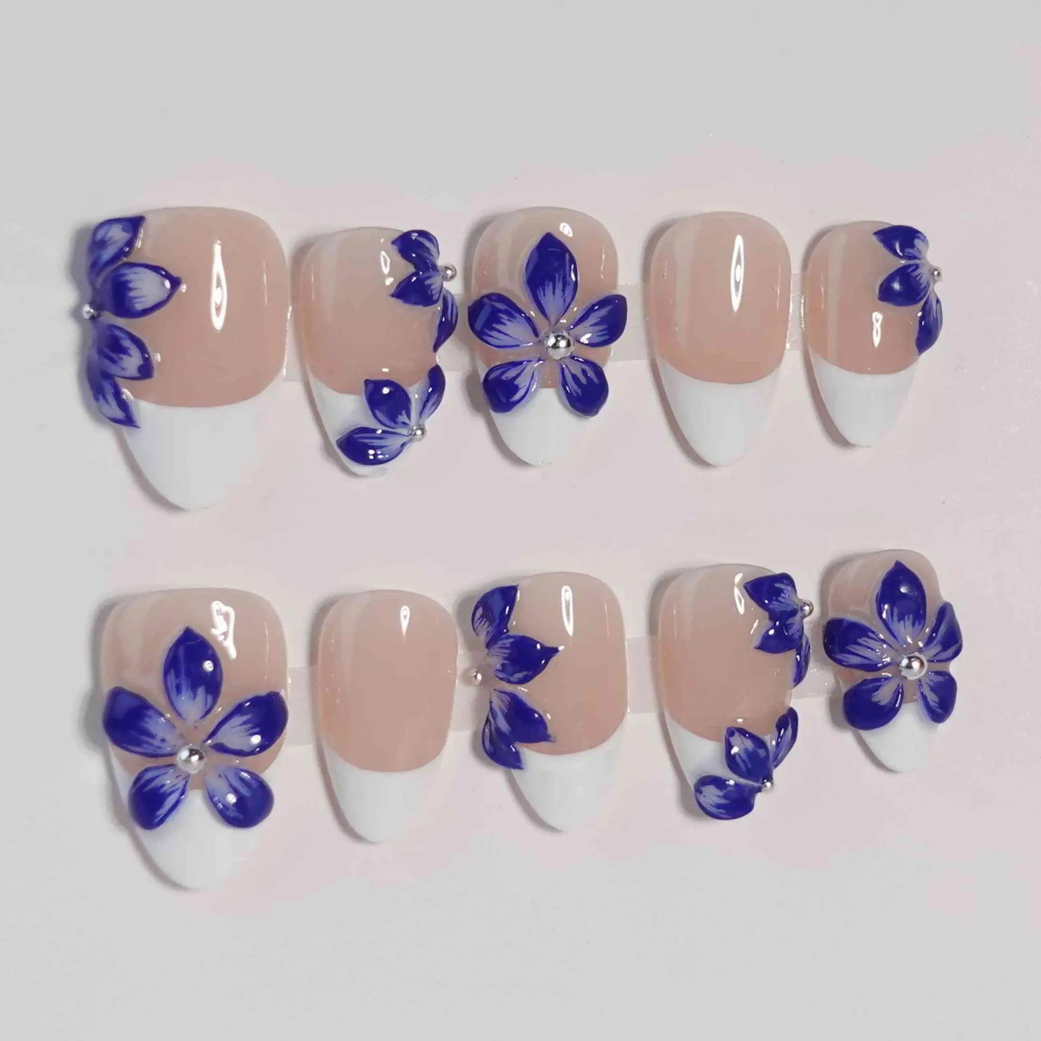 Blue almond press-on nails featuring hand-painted floral accents on clear and nude bases, styled for summer and everyday wear.