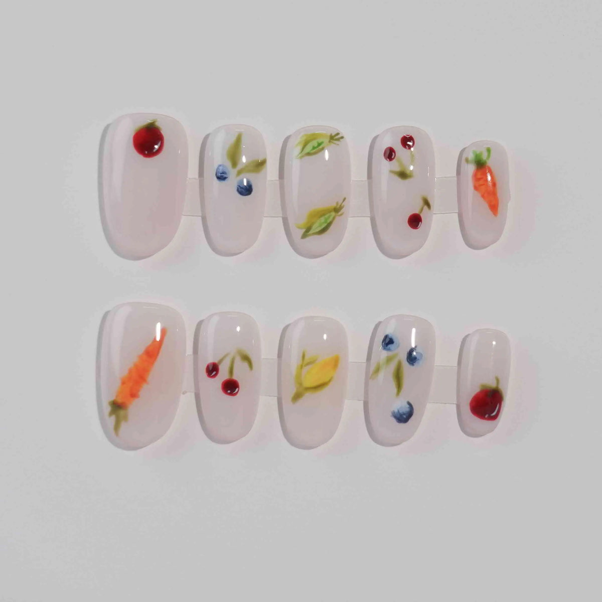 Clear medium oval press on nails with fruit and vegetable accents for a playful summer look.