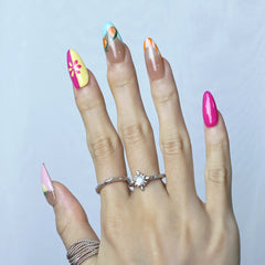 Hand model wearing almond-shaped press-on nails with vibrant orange slices and citrus fruit designs