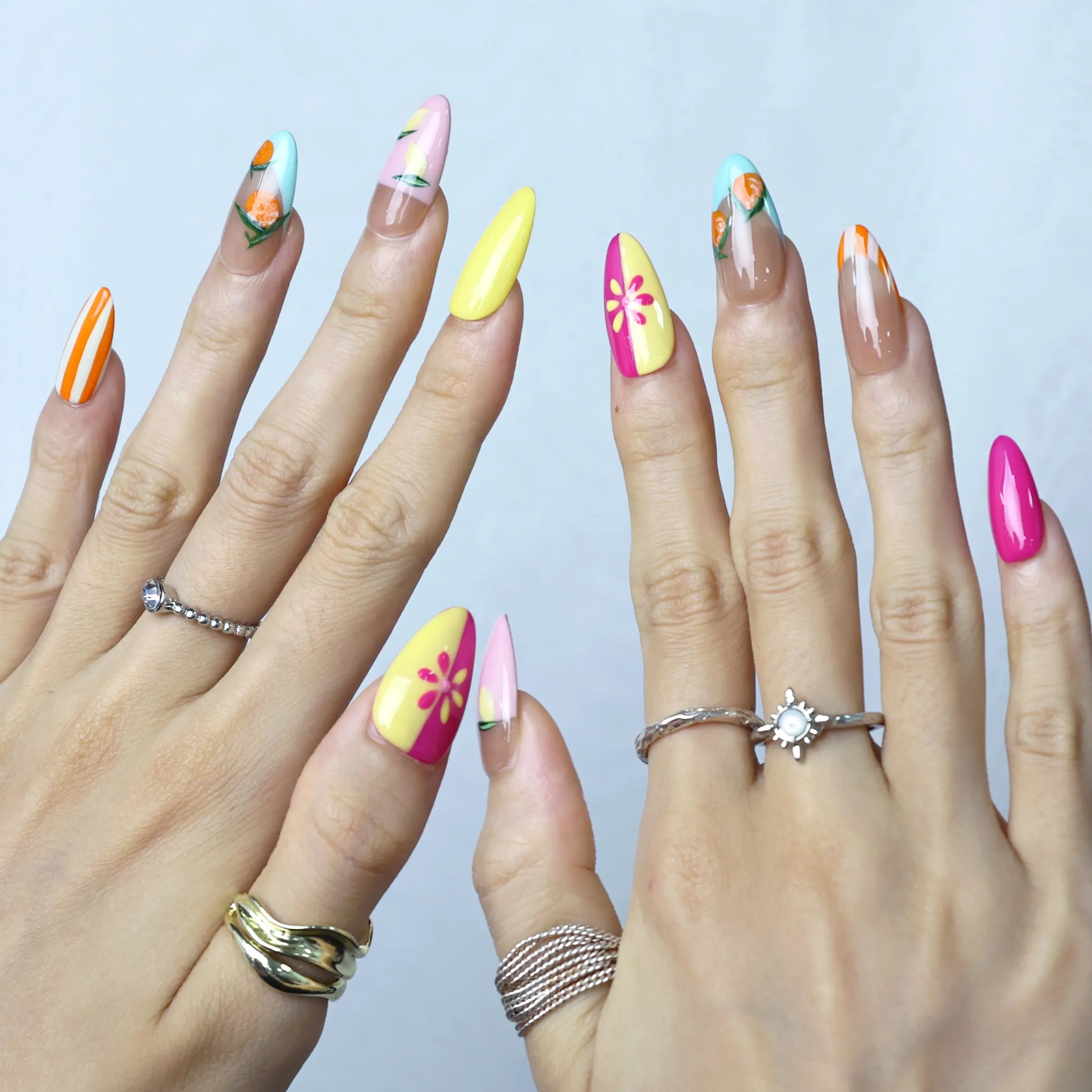 Hand pose showing full citrus nail art in almond shape with juicy orange and grapefruit detail