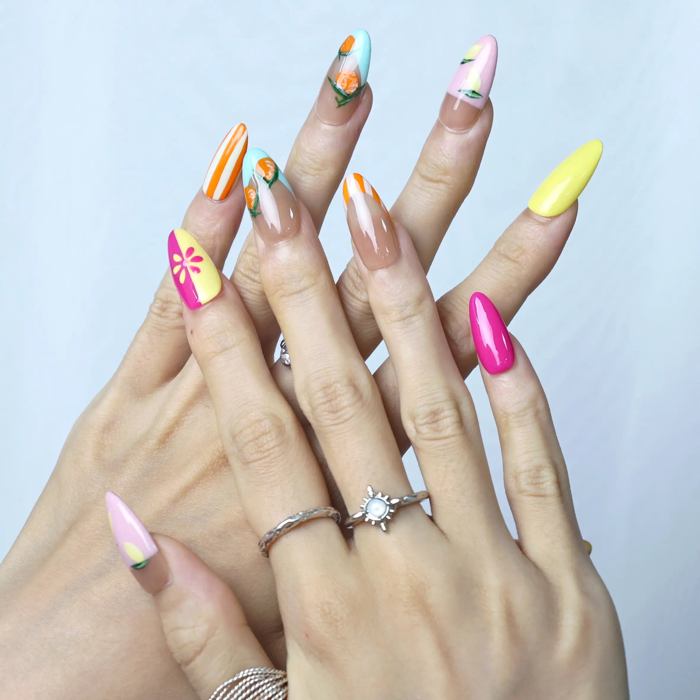 Bright almond nails with hand-painted orange fruits and lemon accents for a cheerful summer vibe