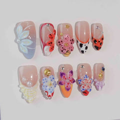 Almond press-on nails featuring 3D butterflies, pink flowers, and ladybug accents—whimsical cottagecore nail art for spring.