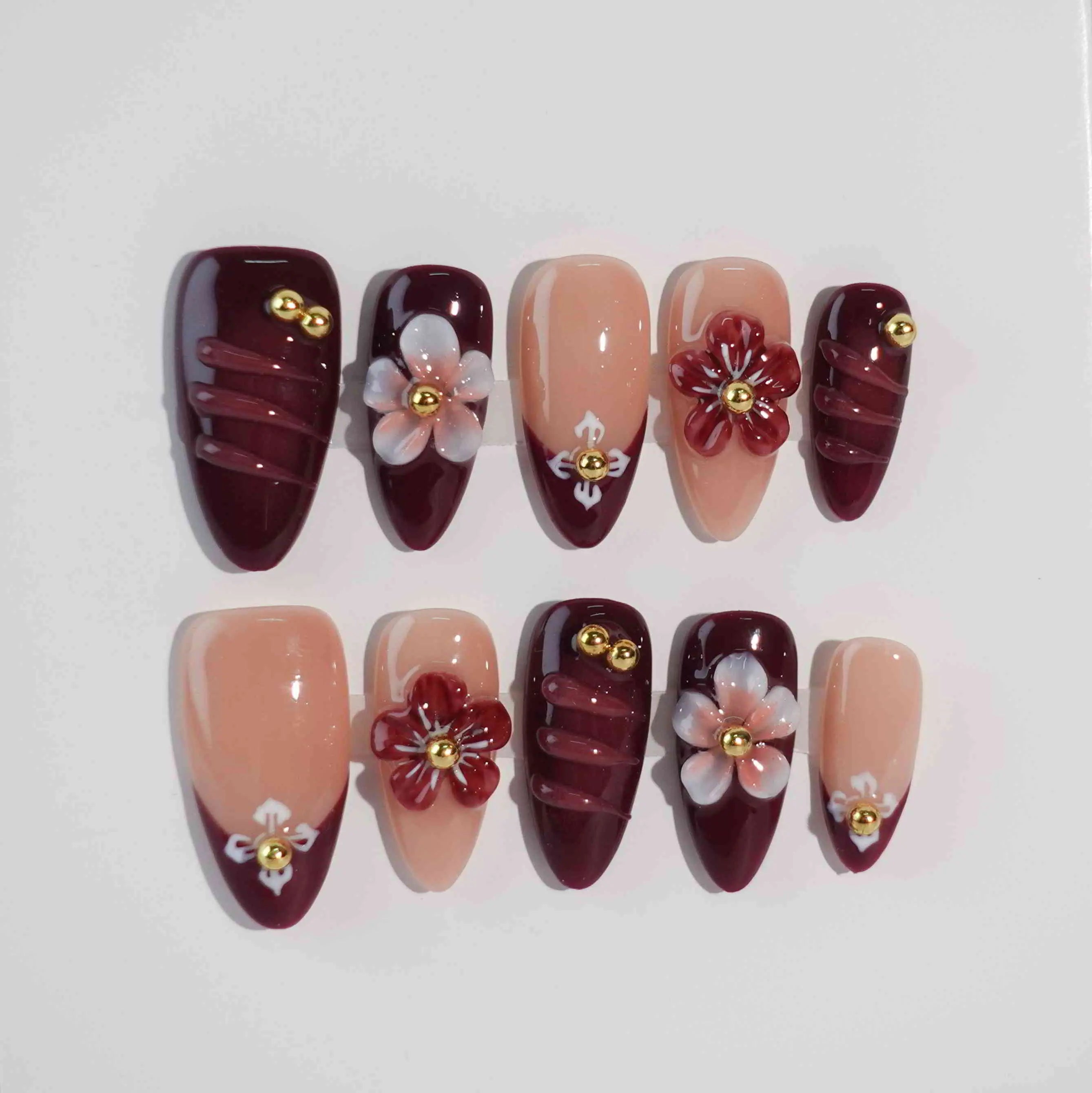 Red almond press on nails with white 3D floral accents and pearls over a nude base—ideal for weddings or formal events.