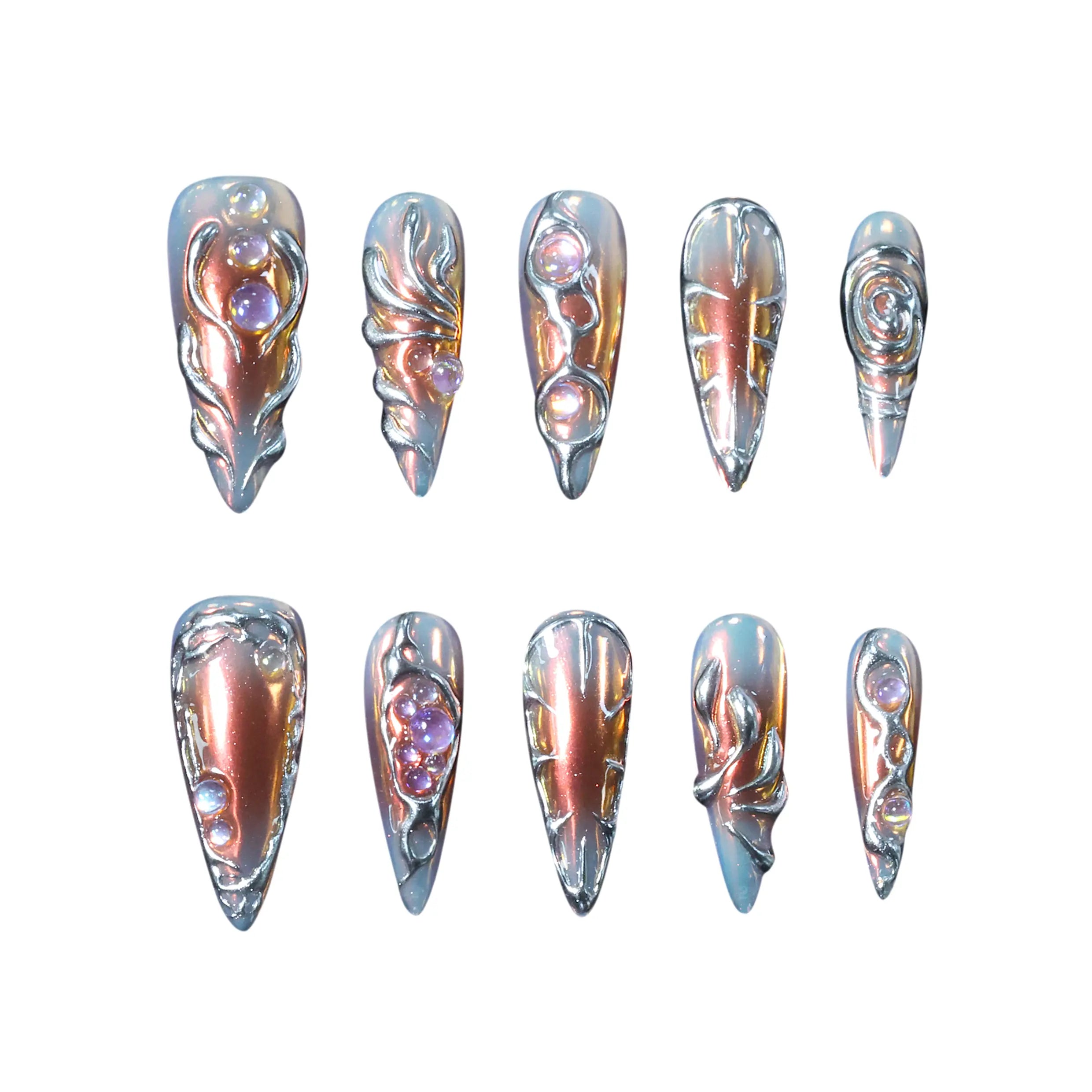 Long stiletto-shaped metallic press-on nails in burnished copper and silver tones with chrome and gem details, creating a molten 3D effect.