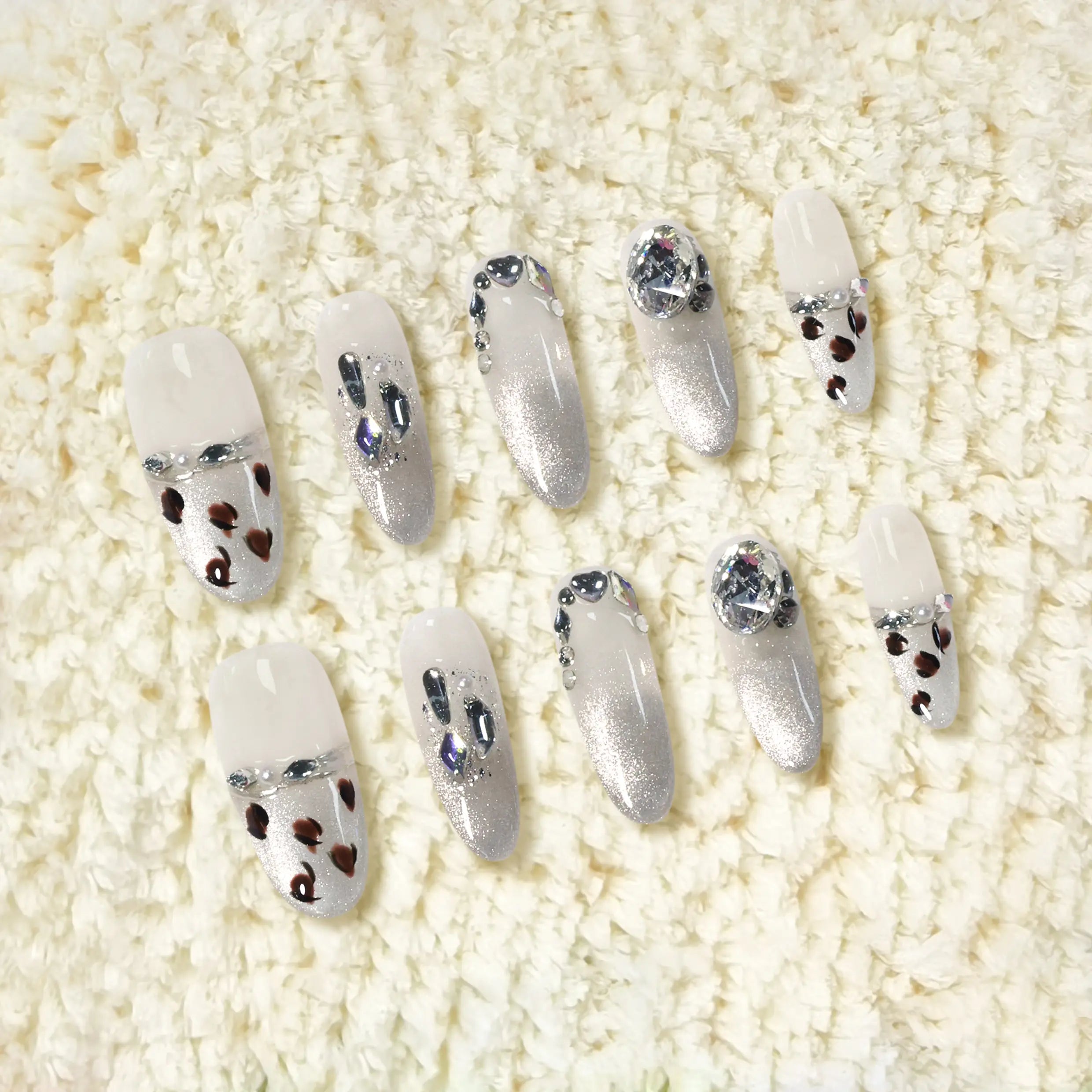 Long oval press on nails with sheer base, silver glitter ombré, and heart-shaped leopard spot accents for a bold summer glam style