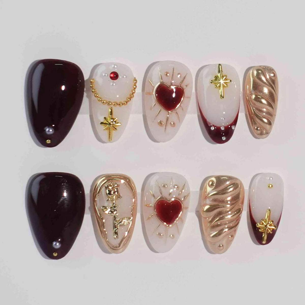 Red almond press-on nails with gold hearts and royal accents, perfect for Valentine’s or romantic evenings.