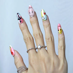 Hand model wearing medium almond nails with pastel pink base, 3D cartoon eyes, and playful clown-style accents