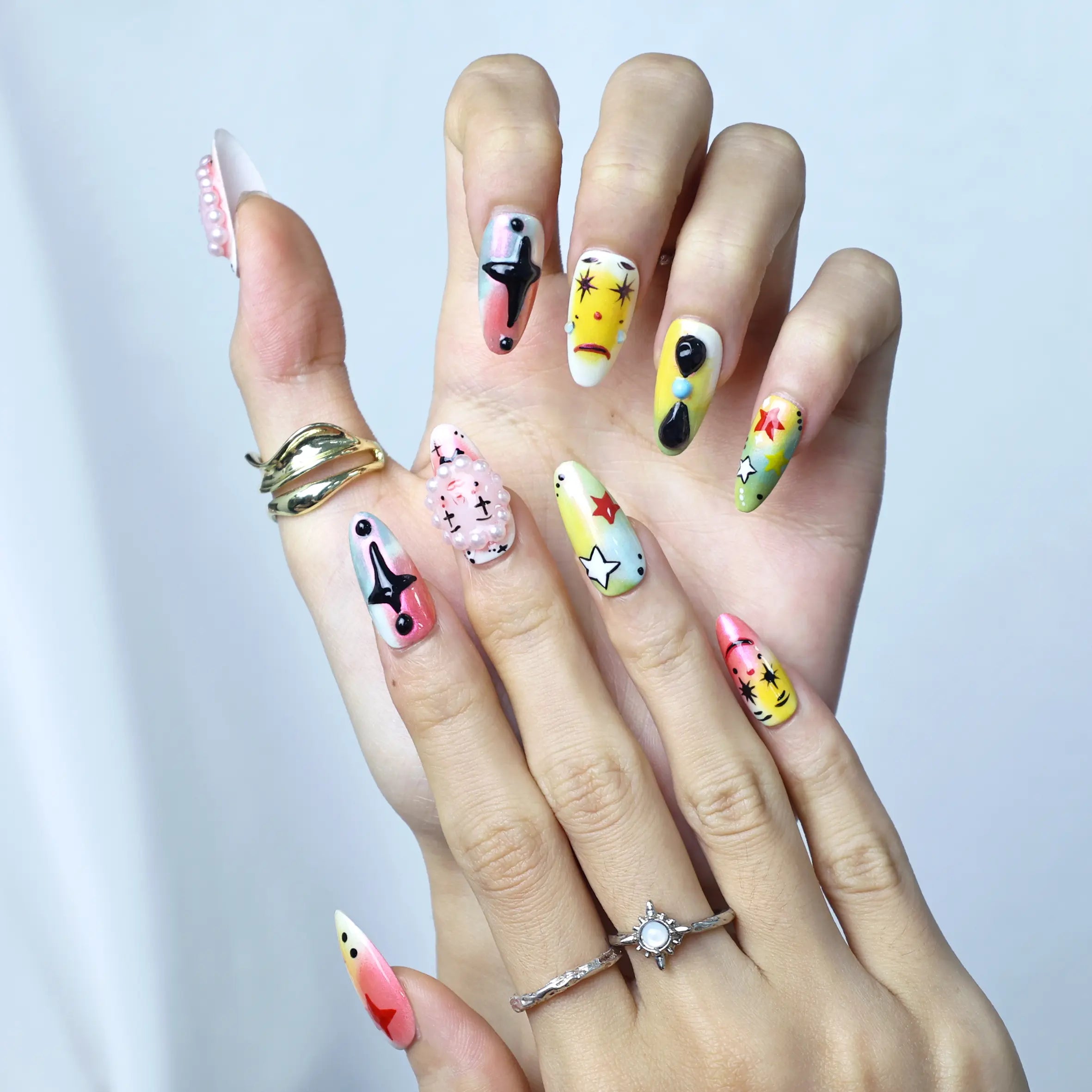 Whimsical nail design in medium almond silhouette with layered cartoon features and a pastel palette