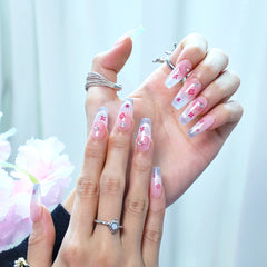 Hand model wearing kawaii pink coffin nails with cute kitten art and sparkling silver tips