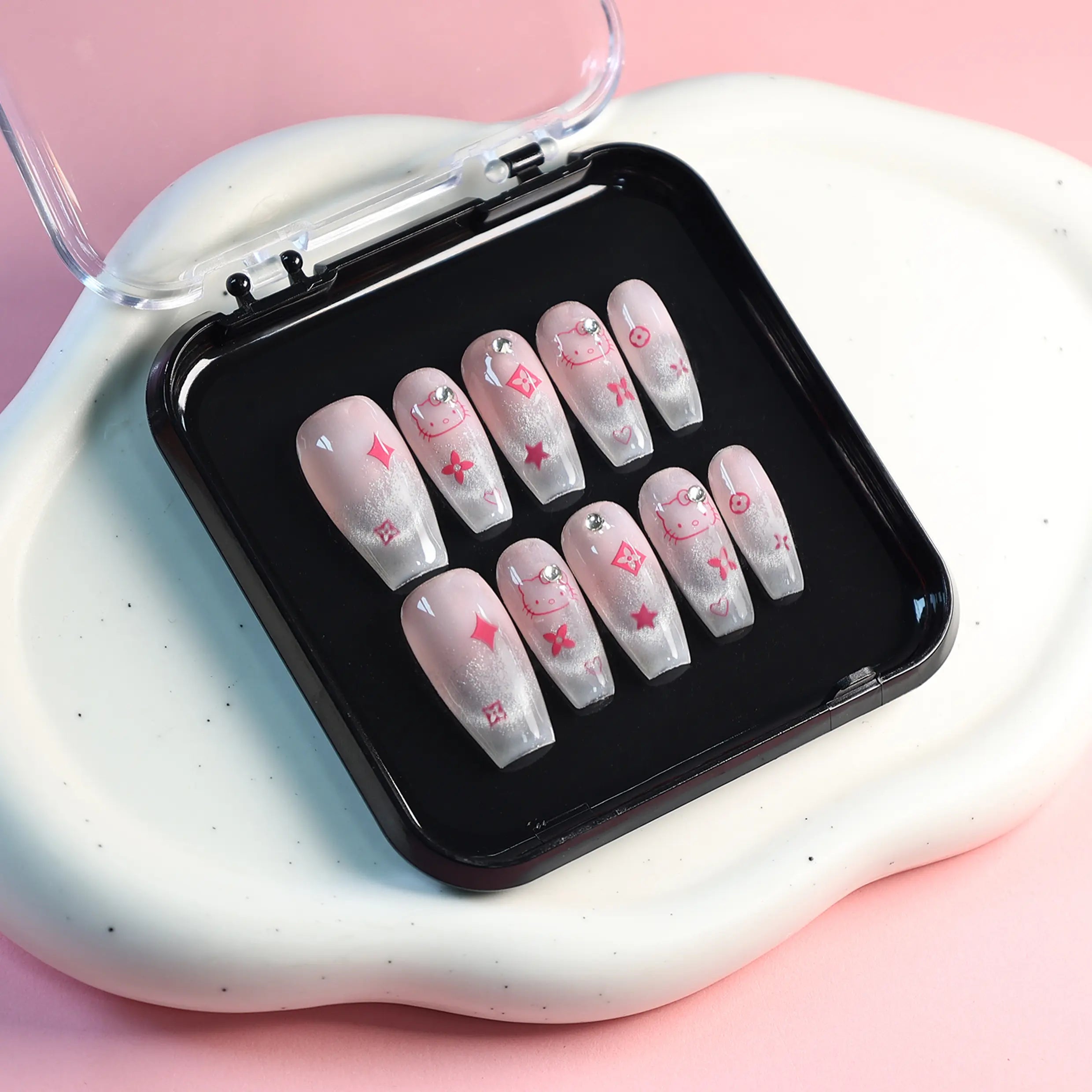 Product layout in display box showing full set of kitten-themed pink coffin nails with glitter and bows