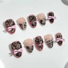 Medium almond press on nails with black lace detail and pink bow accents.