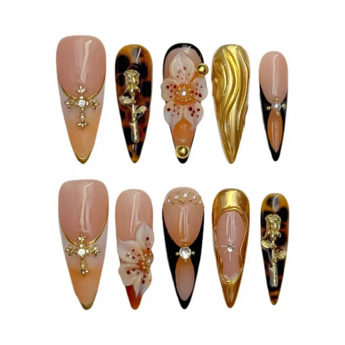 Stiletto-shaped long press on nails in amber tones with gold flames and floral crystals.