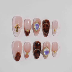 Almond press on nails with tortoiseshell marble, nude base, and lavender gem accents – elegant and luxurious.