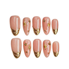 Minimalist medium almond french tip press on nails in nude and gold with gemstone details.