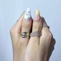 Hand model wearing medium almond nails in soft pink with hand-painted floral accents and tiny fruit charms