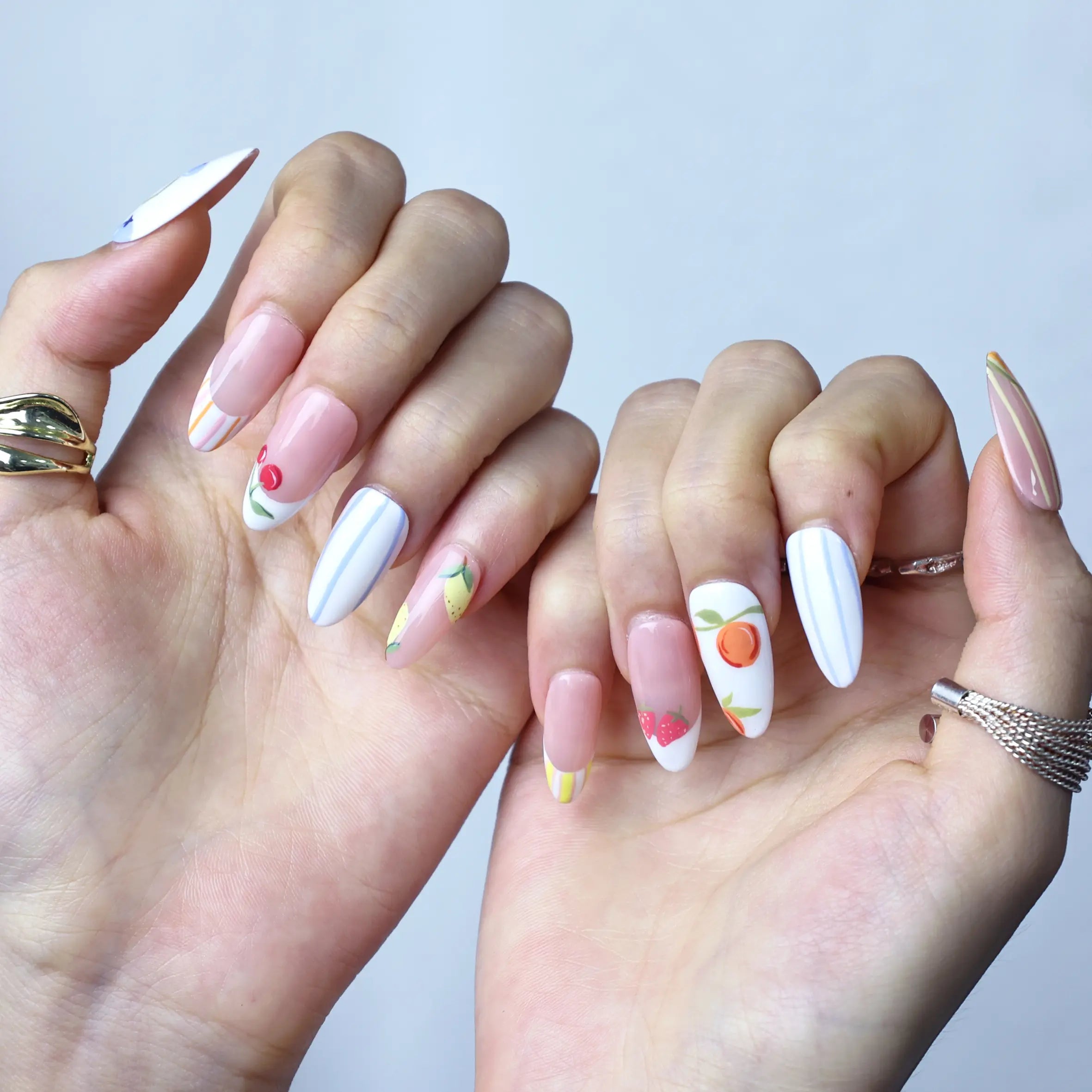Romantic pink press-on nails with dainty flowers and juicy fruit motifs in a cute almond silhouette
