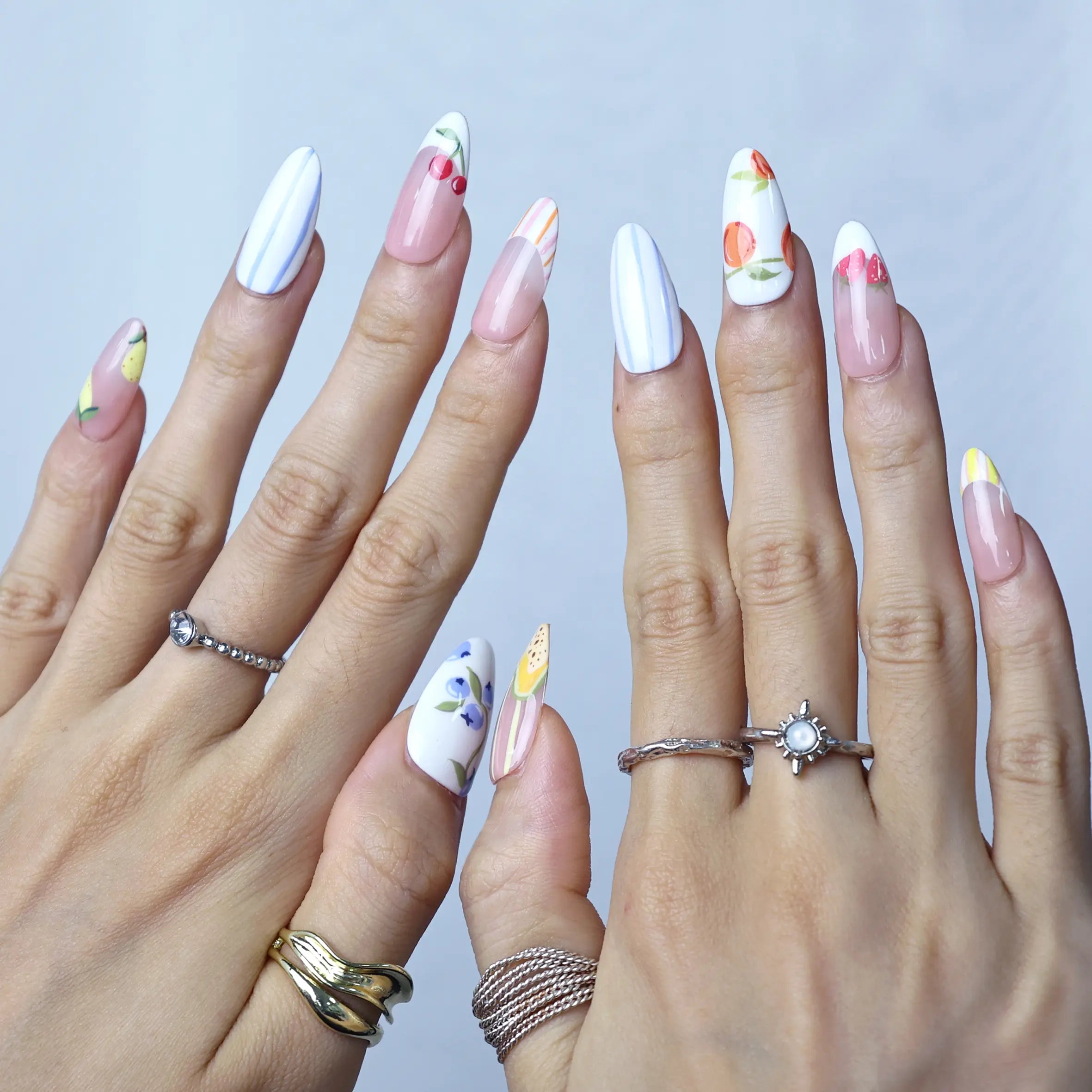 Elegant soft pink nails with floral prints, raised fruit details, and a medium almond shape for daily wear