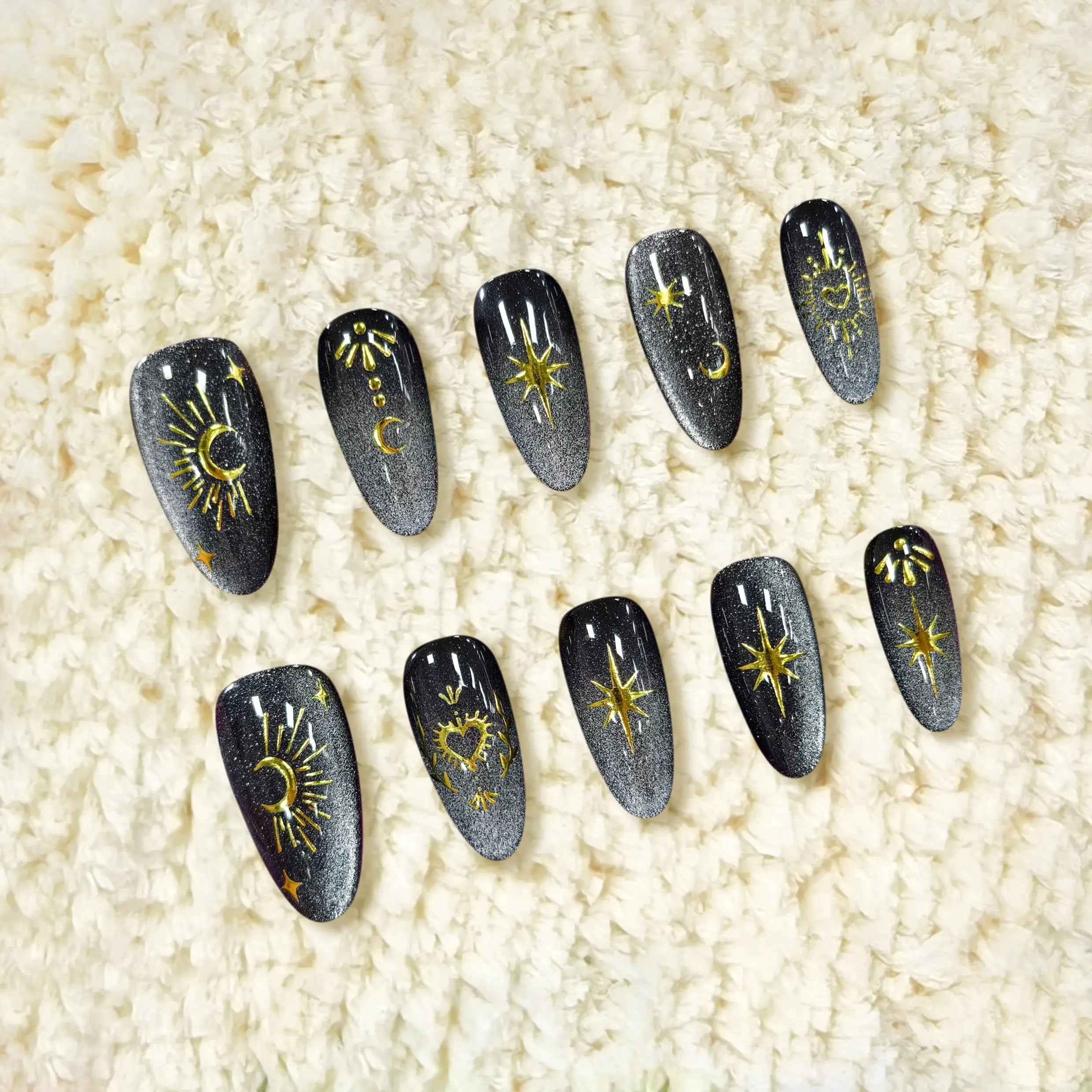 Medium almond black press-on nails with silver gradient, gold moon and star accents, and a shimmering cosmic design.