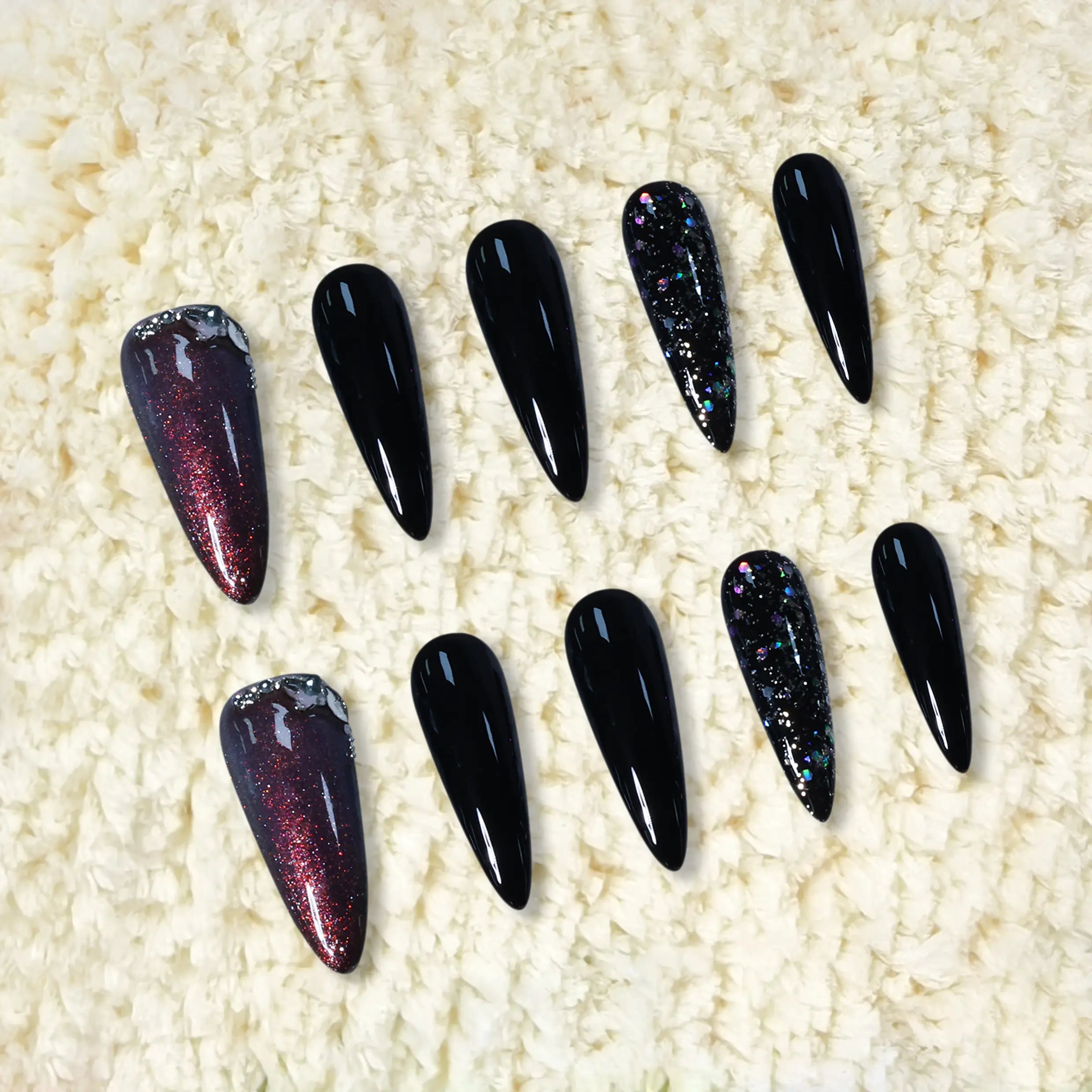 Long black stiletto press-on nails with red glitter and galaxy sparkle accents, inspired by the night sky.