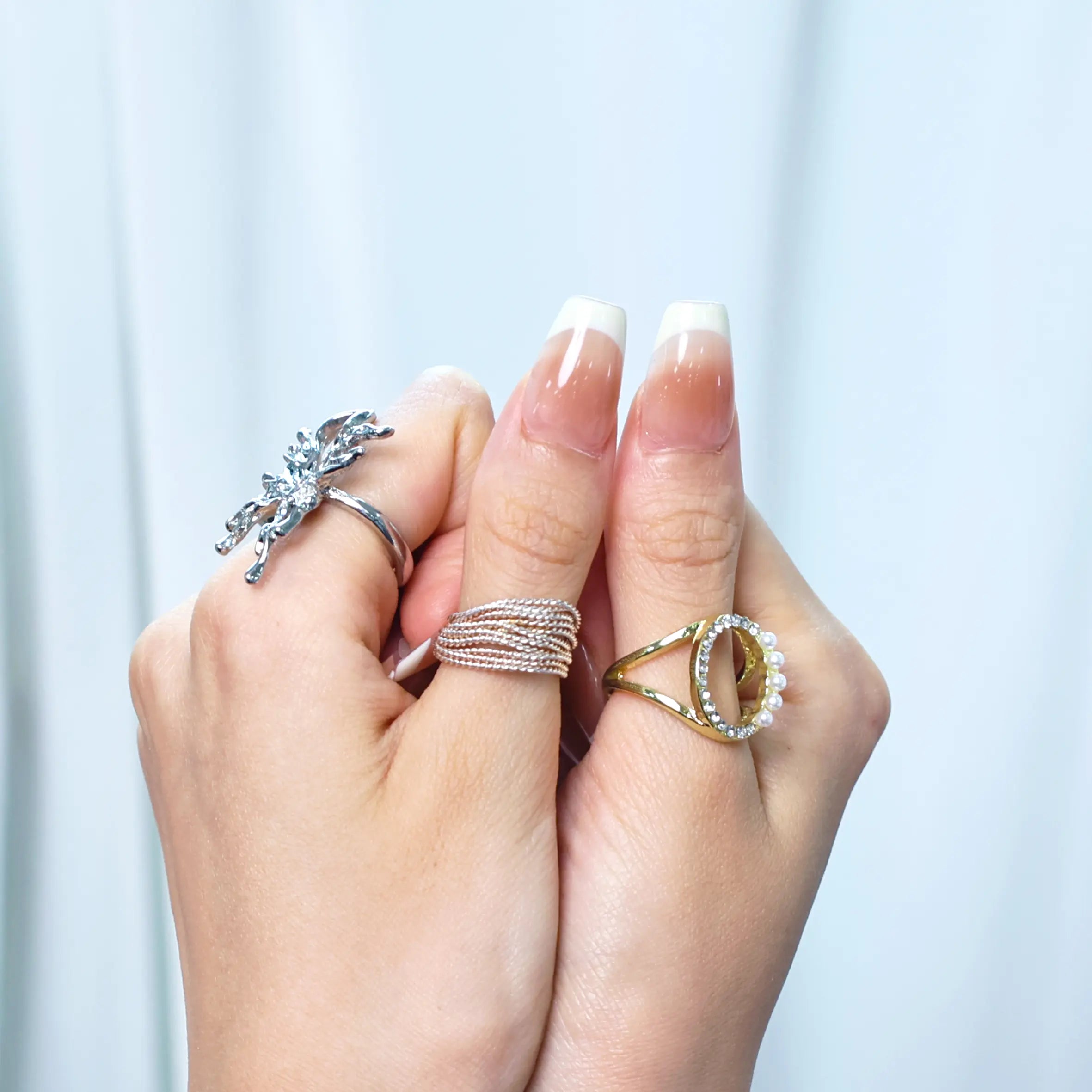 Lifestyle image featuring French tip nails on hand with rings