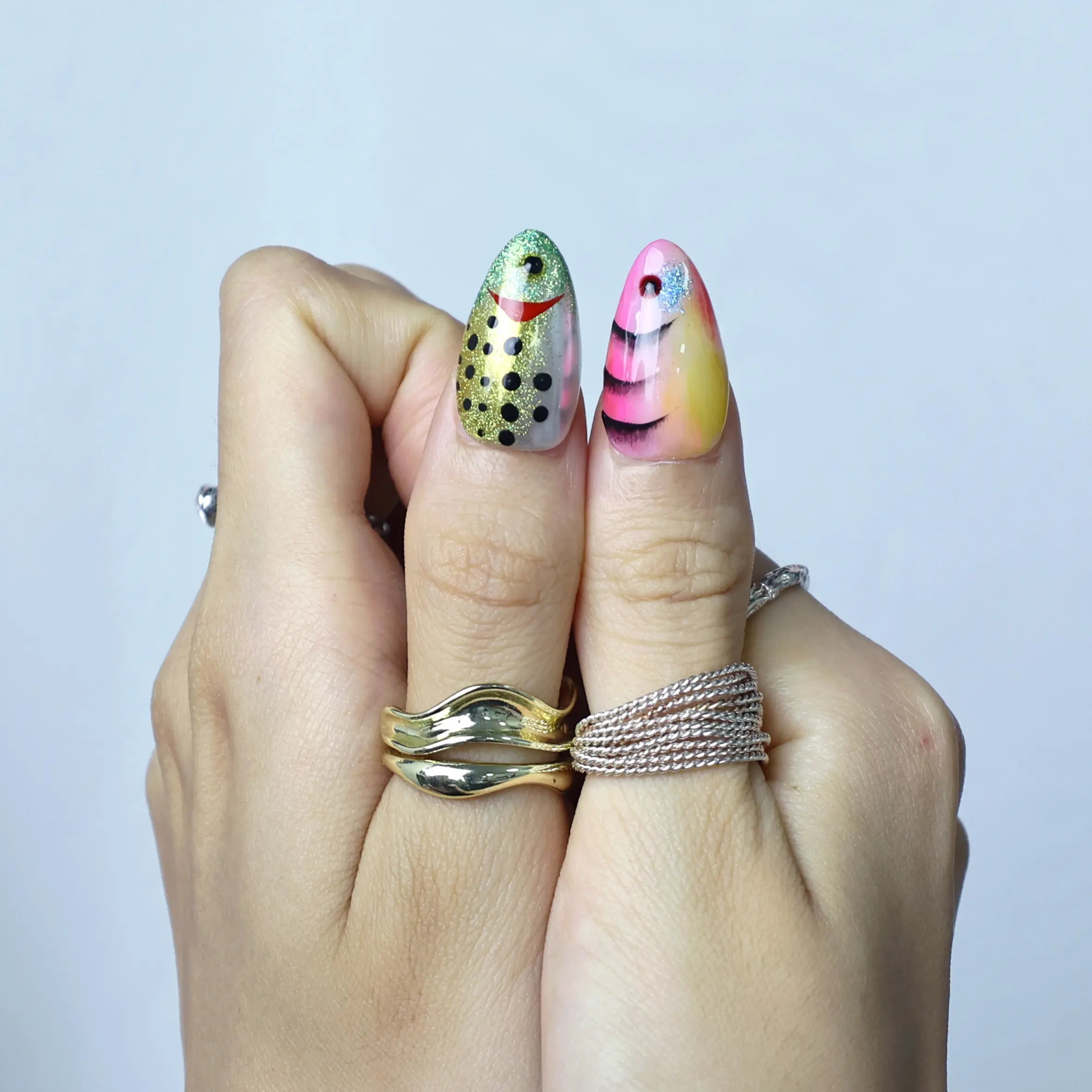 Close-up of press-on nails with ocean-inspired design featuring layered scales and reflective blue finish