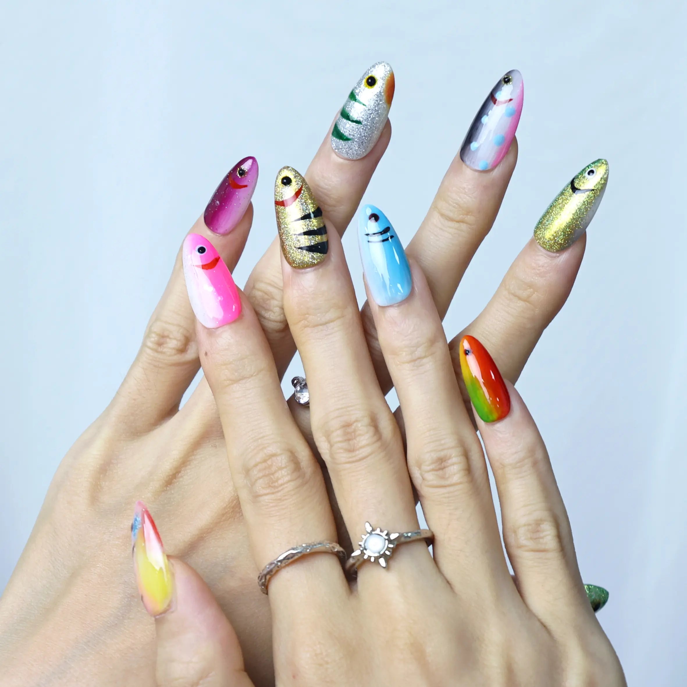 Hand pose showing elegant almond nails in metallic blue with detailed scale design and a wave-like shimmer